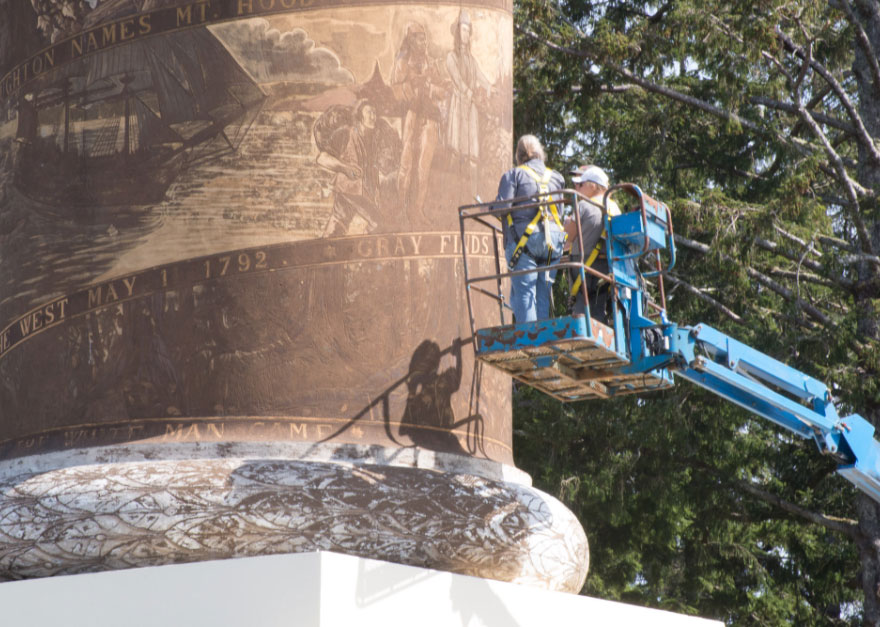 A restoration crew on a lift discusses their work on the Astoria Column